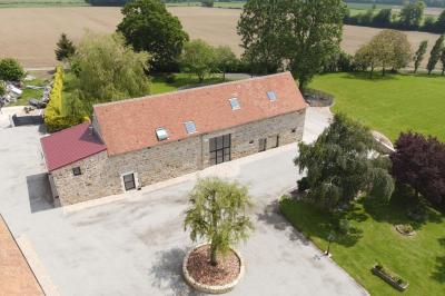Salle en pierre décorée avec des cadres photo, des chaises blanches et des bougies sur une table.