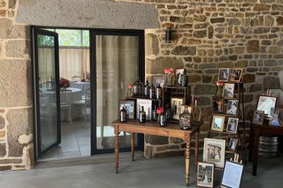 Salle en pierre décorée avec des cadres photo, des chaises blanches et des bougies sur une table.