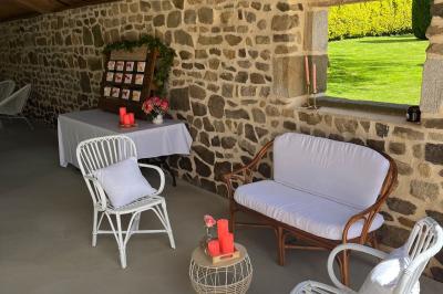Salle en pierre décorée avec des cadres photo, des chaises blanches et des bougies sur une table.