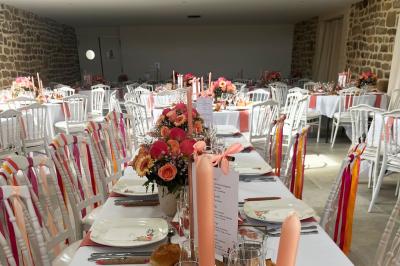 Salle en pierre décorée avec des cadres photo, des chaises blanches et des bougies sur une table.