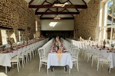 Salle en pierre décorée avec des cadres photo, des chaises blanches et des bougies sur une table.