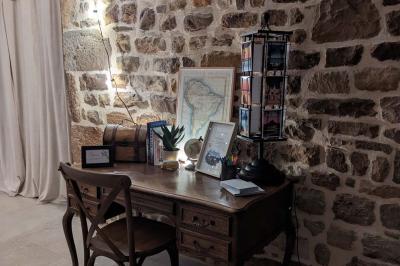 Salle en pierre décorée avec des cadres photo, des chaises blanches et des bougies sur une table.