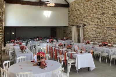 Salle en pierre décorée avec des cadres photo, des chaises blanches et des bougies sur une table.