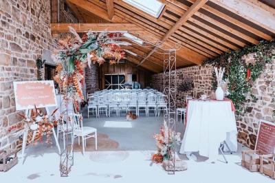 Salle en pierre décorée avec des cadres photo, des chaises blanches et des bougies sur une table.