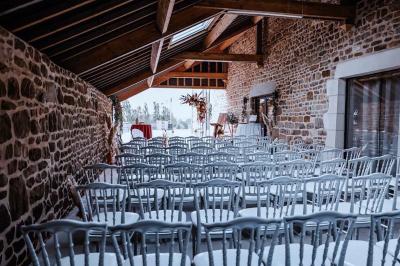 Salle en pierre décorée avec des cadres photo, des chaises blanches et des bougies sur une table.