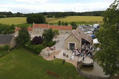 Salle en pierre décorée avec des cadres photo, des chaises blanches et des bougies sur une table.