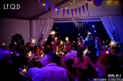 Un couple de mariés s'embrasse sous une haie d'honneur formée par des pompiers tenant des roses rouges.