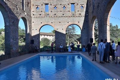 Un couple de mariés s'embrasse sous une haie d'honneur formée par des pompiers tenant des roses rouges.