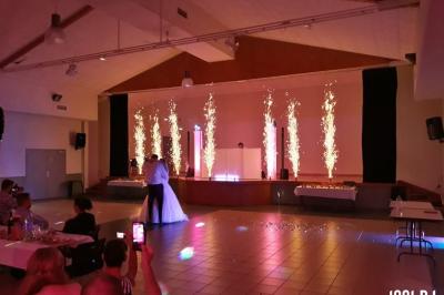 Un couple de mariés s'embrasse sous une haie d'honneur formée par des pompiers tenant des roses rouges.