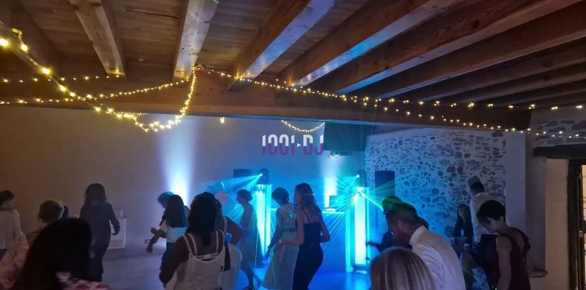 Des personnes dansent dans une salle éclairée par des guirlandes lumineuses et des projecteurs colorés.