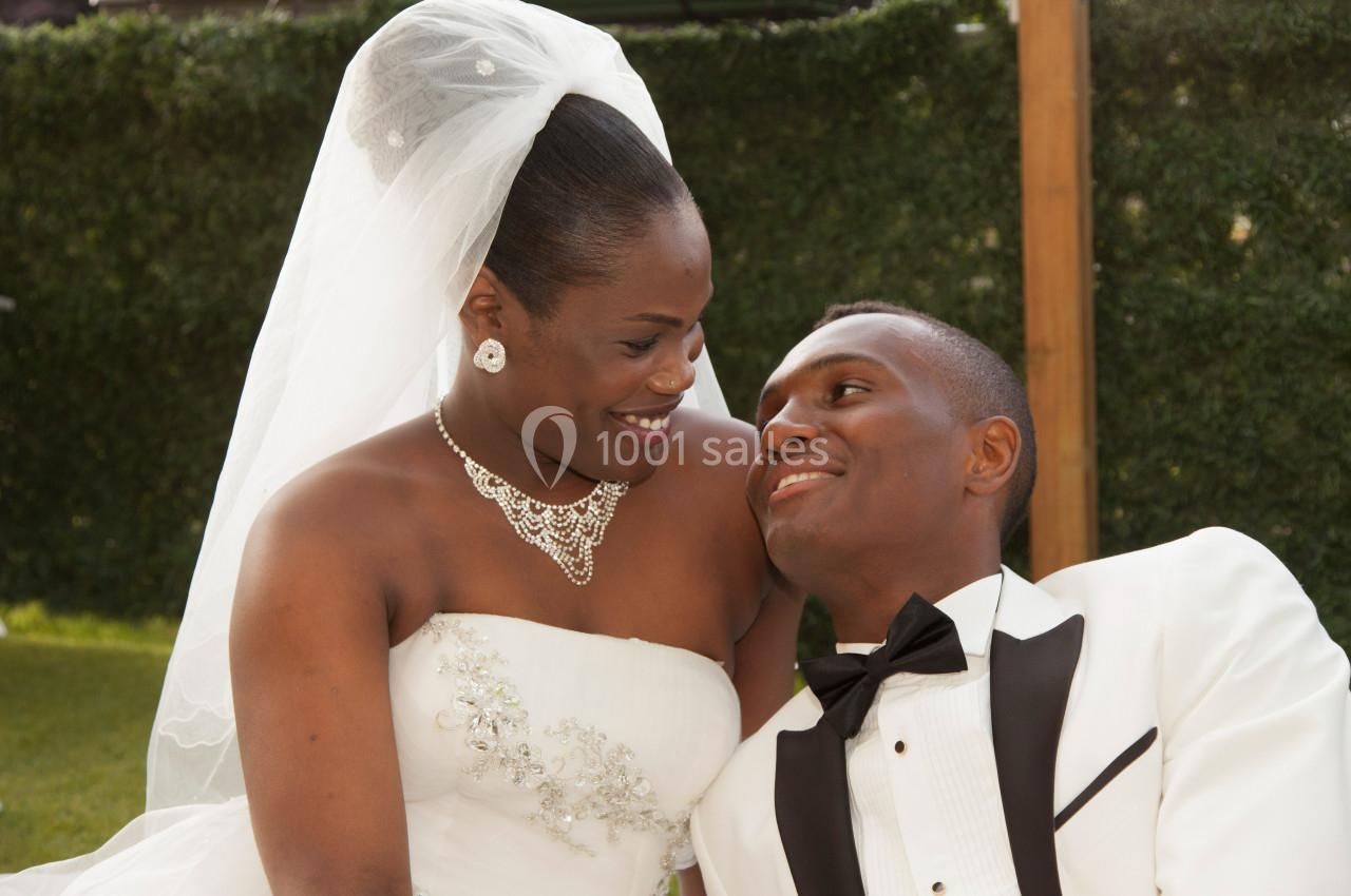 Un couple en tenue de mariage se regarde avec tendresse dans un jardin.
