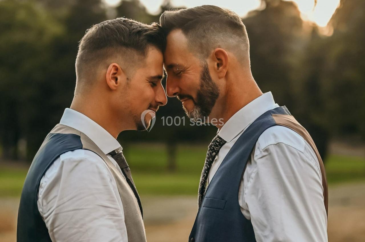 Deux hommes en gilets et chemises blanches se tiennent tête contre tête dans un parc au coucher du soleil.