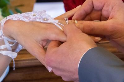 Une mariée glisse une alliance au doigt de son partenaire lors d'une cérémonie de mariage.