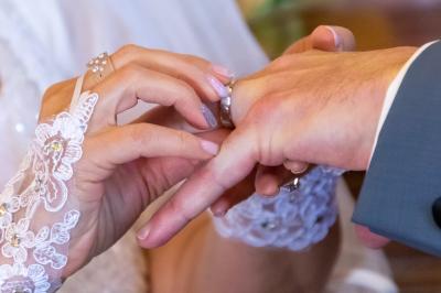 Une mariée glisse une alliance au doigt de son partenaire lors d'une cérémonie de mariage.