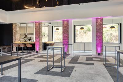 Façade moderne d'un hôtel Mercure avec des voitures circulant devant, entouré d'arbres et d'un ciel partiellement nuageux.