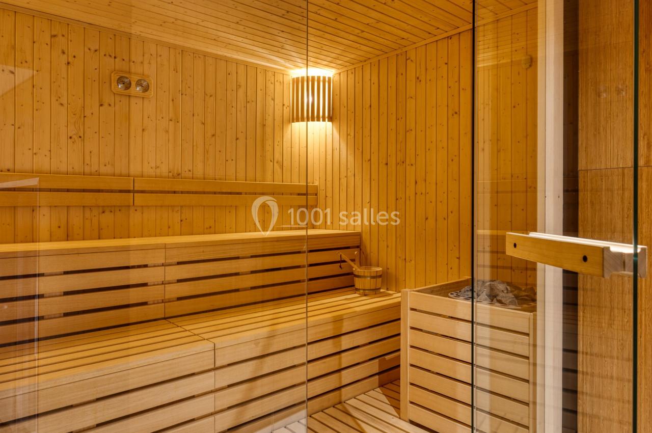 Intérieur d'un sauna en bois avec bancs, seau en bois et lumière douce.