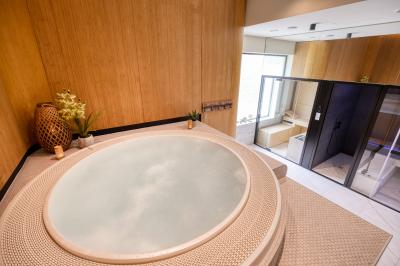 Façade moderne d'un hôtel Mercure avec des voitures circulant devant, entouré d'arbres et d'un ciel partiellement nuageux.