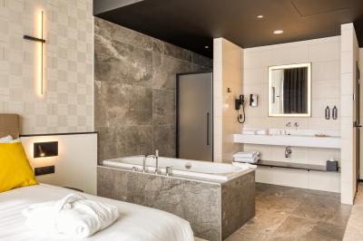 Façade moderne d'un hôtel Mercure avec des voitures circulant devant, entouré d'arbres et d'un ciel partiellement nuageux.