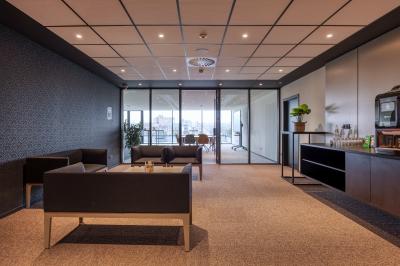 Terrasse moderne avec mobilier vert et blanc, vue sur une rivière et des bâtiments en arrière-plan.