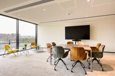 Terrasse moderne avec mobilier vert et blanc, vue sur une rivière et des bâtiments en arrière-plan.