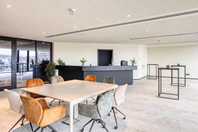 Terrasse moderne avec mobilier vert et blanc, vue sur une rivière et des bâtiments en arrière-plan.