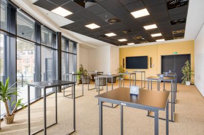 Terrasse moderne avec mobilier vert et blanc, vue sur une rivière et des bâtiments en arrière-plan.