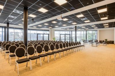 Terrasse moderne avec mobilier vert et blanc, vue sur une rivière et des bâtiments en arrière-plan.