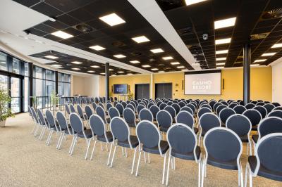 Terrasse moderne avec mobilier vert et blanc, vue sur une rivière et des bâtiments en arrière-plan.