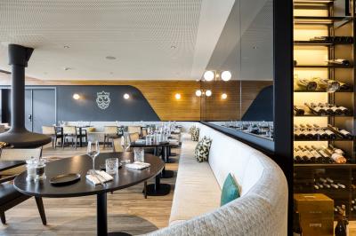 Terrasse moderne avec mobilier vert et blanc, vue sur une rivière et des bâtiments en arrière-plan.