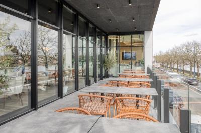 Terrasse moderne avec mobilier vert et blanc, vue sur une rivière et des bâtiments en arrière-plan.