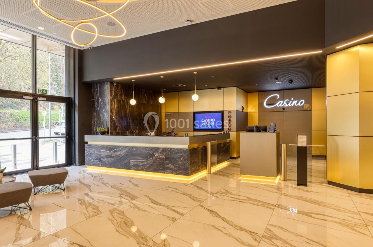 Hall d'entrée moderne avec comptoir d'accueil, sol en marbre, éclairage design et vue sur l'extérieur vitré.