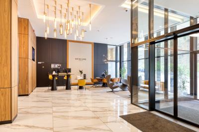 Terrasse moderne avec mobilier vert et blanc, vue sur une rivière et des bâtiments en arrière-plan.