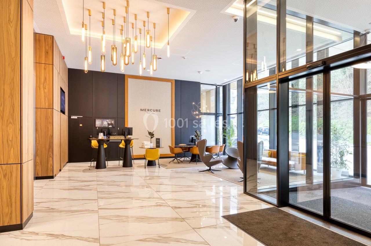 Hall d'entrée moderne avec sol en marbre, mobilier design, éclairage suspendu et grandes baies vitrées.