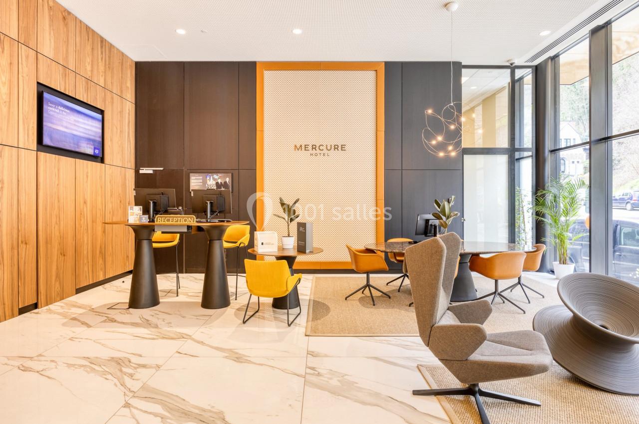 Hall d'accueil moderne avec comptoir de réception, fauteuils design, et décoration chaleureuse en bois et marbre.