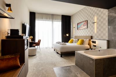 Terrasse moderne avec mobilier vert et blanc, vue sur une rivière et des bâtiments en arrière-plan.