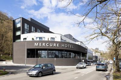 Terrasse moderne avec mobilier vert et blanc, vue sur une rivière et des bâtiments en arrière-plan.