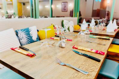 Salle de restaurant lumineuse avec tables en bois dressées, plafond décoré de guirlandes végétales et grandes baies vitrées.