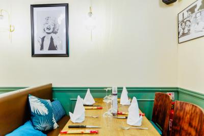 Salle de restaurant lumineuse avec tables en bois dressées, plafond décoré de guirlandes végétales et grandes baies vitrées.