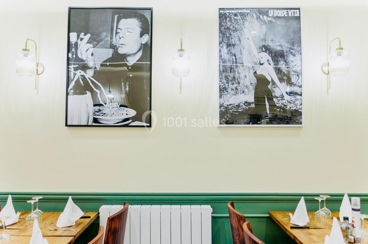 Deux affiches en noir et blanc décorent un mur clair au-dessus de tables dressées dans un restaurant.