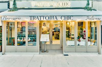 Façade d'un restaurant italien avec vitrines éclairées, menu extérieur et décorations de Noël sur le trottoir.