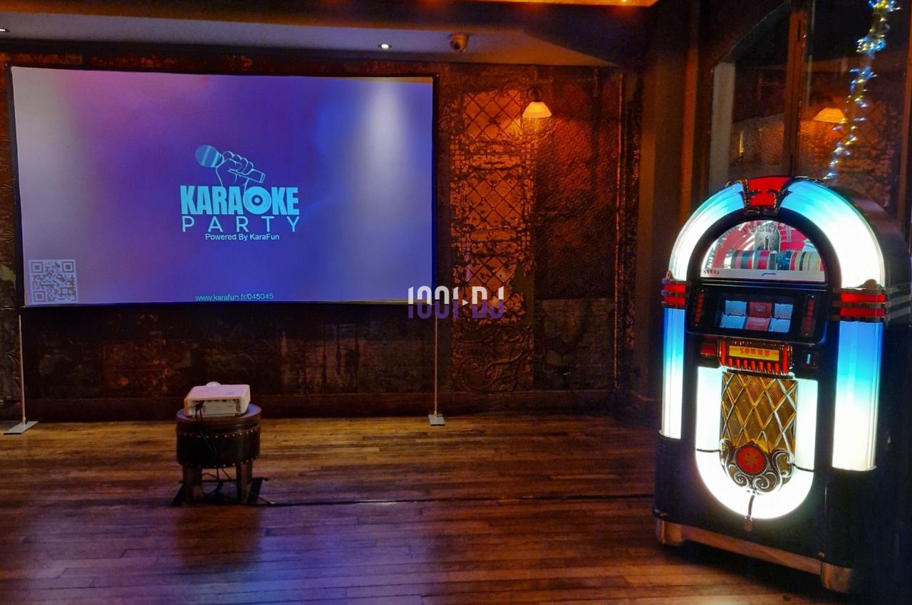 Salle de karaoké avec un jukebox lumineux à droite et un écran de projection affichant ’Karaoke Party’.