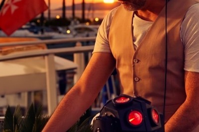 Un DJ mixe sur scène devant un écran géant projetant une vidéo d'une danseuse en tenue scintillante.