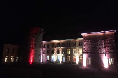 Salle de réception élégante avec tables dressées, chaises blanches, décorations florales et un piano en arrière-plan.