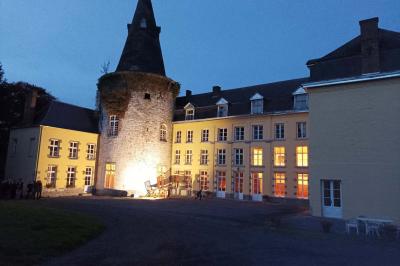 Salle de réception élégante avec tables dressées, chaises blanches, décorations florales et un piano en arrière-plan.