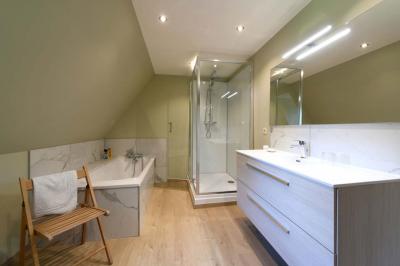 Salle de réception élégante avec tables dressées, chaises blanches, décorations florales et un piano en arrière-plan.