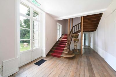 Salle de réception élégante avec tables dressées, chaises blanches, décorations florales et un piano en arrière-plan.