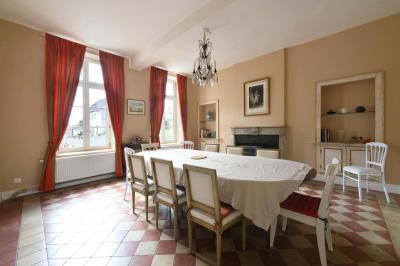 Salle de réception élégante avec tables dressées, chaises blanches, décorations florales et un piano en arrière-plan.