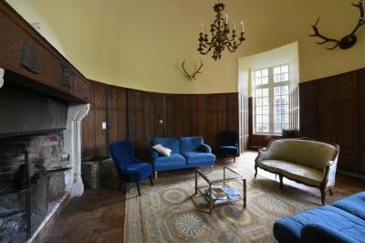 Salle de réception élégante avec tables dressées, chaises blanches, décorations florales et un piano en arrière-plan.