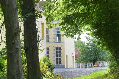 Salle de réception élégante avec tables dressées, chaises blanches, décorations florales et un piano en arrière-plan.
