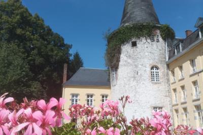 Salle de réception élégante avec tables dressées, chaises blanches, décorations florales et un piano en arrière-plan.